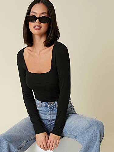 Woman wearing a black top and sunglasses sitting on a stool.